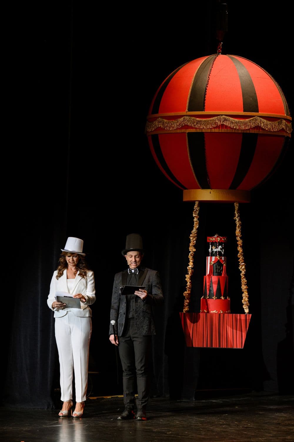 Két műsorvezető a színpadon egy óriási hőlégballon formájú évfordulós torta mellett