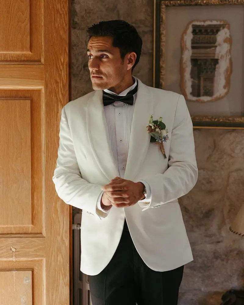Vőlegény fehér szmokingkabátban, díszes boutonniere-rel